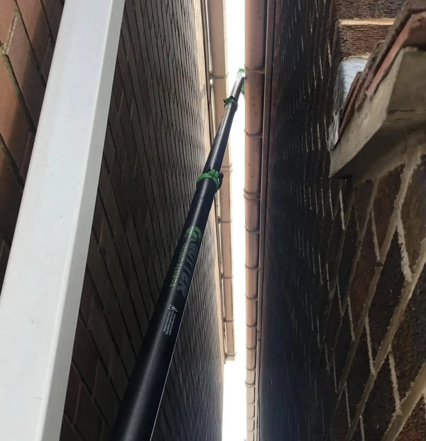 Technician flushing downpipes with hose